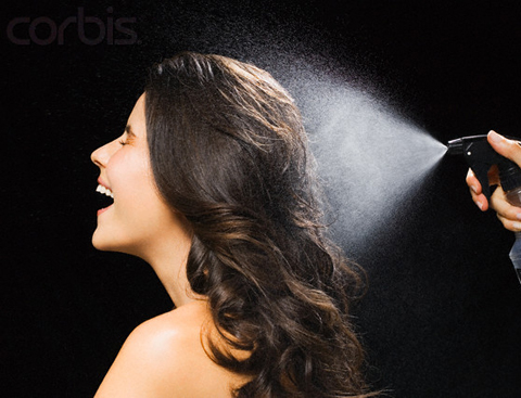 Young Brunette Woman Spraying Hairspray --- Image by © Joerg Steffens/Corbis