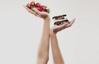 Woman cupping strawberries above chocolate bars