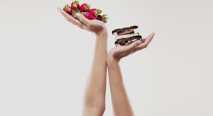 Woman cupping strawberries above chocolate bars