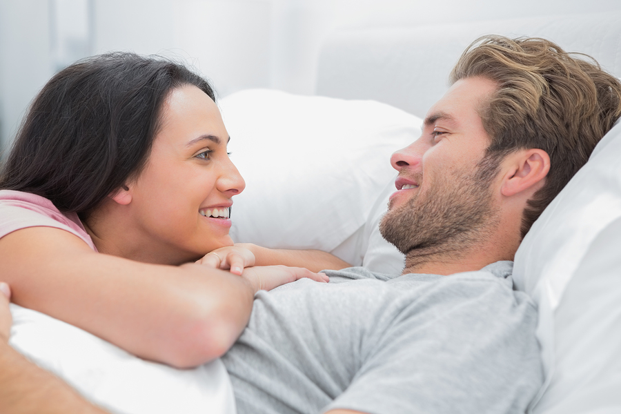 Cheerful couple awaking and looking at each other in bed