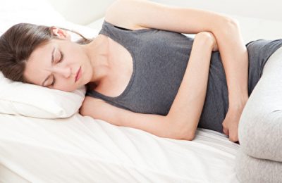 Young woman in pain lying on bed