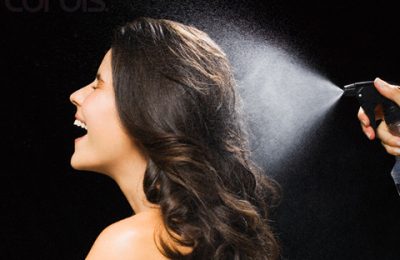 Young Brunette Woman Spraying Hairspray --- Image by © Joerg Steffens/Corbis