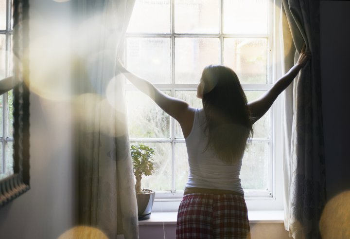 woman opening curtains in the morning