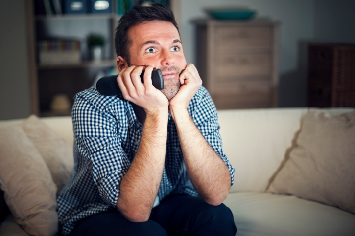 Smiling man watching interesting movie