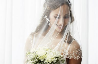 Excited young bride in veil holding bouquet