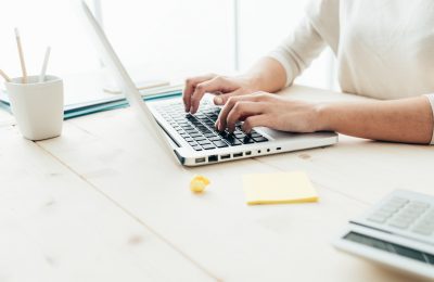 Woman sitting at desk and working at computer hands close up