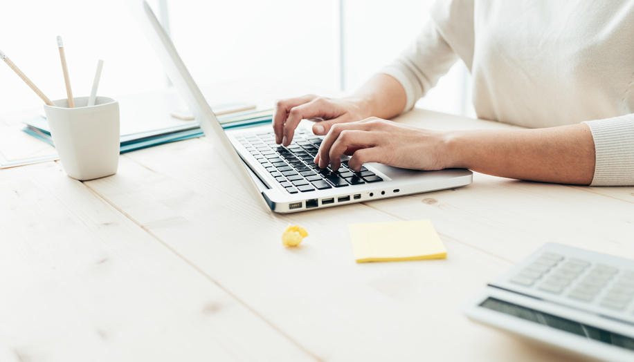 Woman sitting at desk and working at computer hands close up