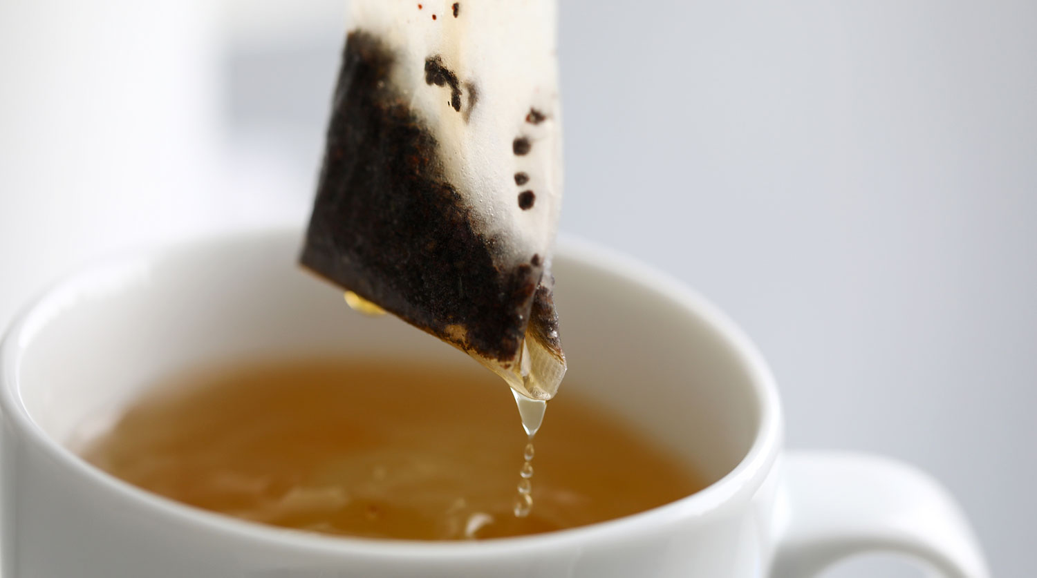 Hot water trickling down from herbal potion teabag close-up