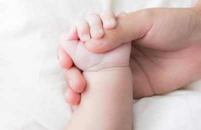 parenting concept with adult holding baby hand